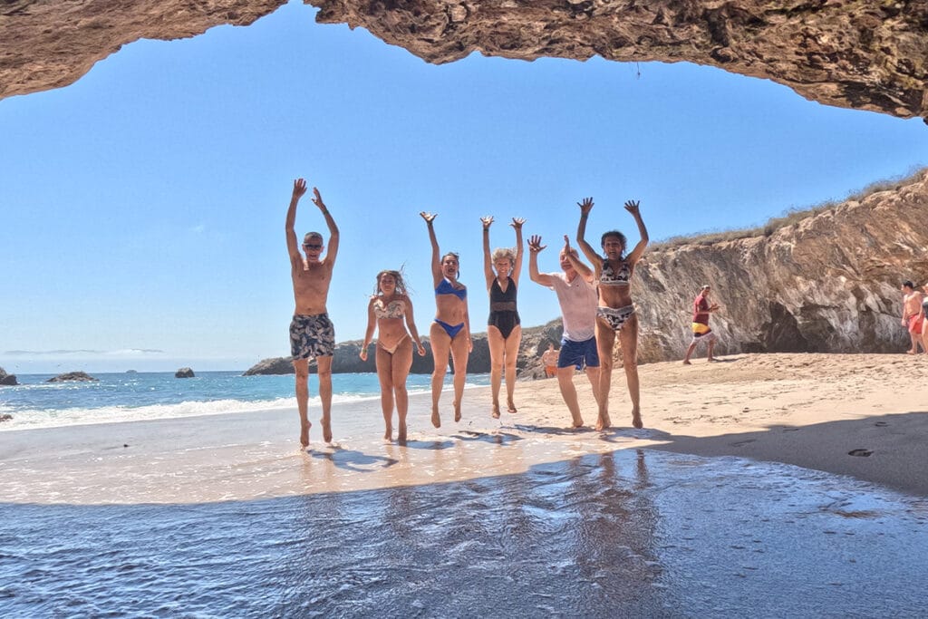 Grupo de amigos saltando de alegría en la playa durante su tour privado Islas Marietas.