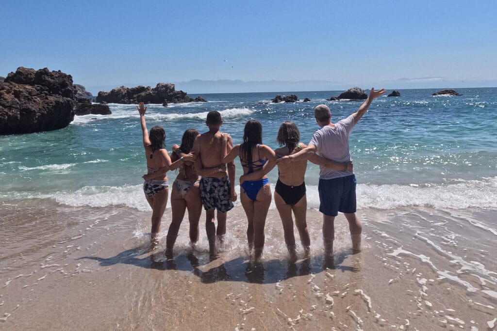 Grupo de amigos abrazados en la playa contemplando el mar en Islas Marietas.